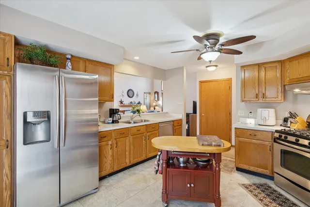 a kitchen with stainless steel appliances a refrigerator a sink a stove and white cabinets