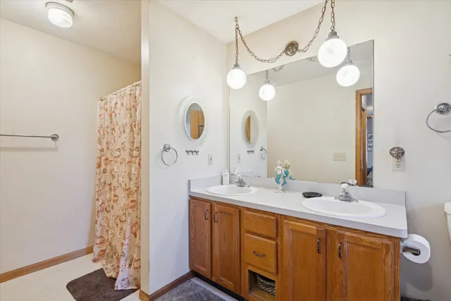 a bathroom with a sink a mirror a light fixture and a glass door shower