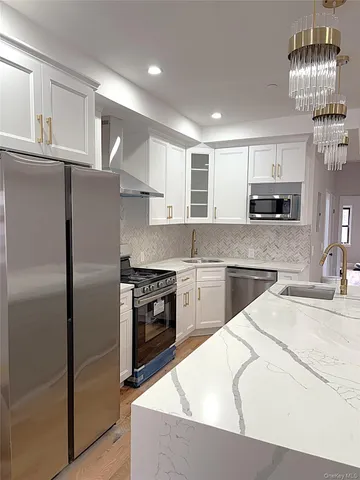 a kitchen with stainless steel appliances granite countertop a refrigerator stove top oven and sink
