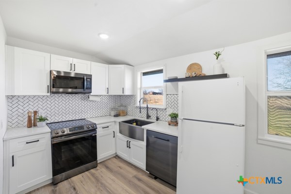 3267 Dairy Road Temple, TX 76501 - Photo 17 of 42 a kitchen with a refrigerator sink and wooden cabinets