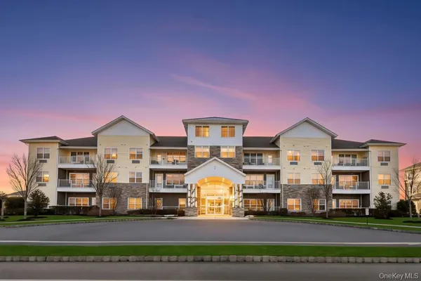 a front view of building with lot of cars and trees
