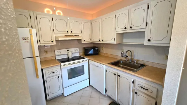 a kitchen with white cabinets and white appliances