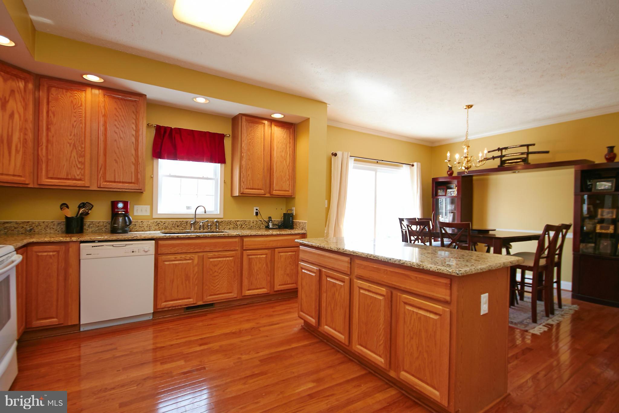 4 Yosemite Ridge Court Stafford, VA 22554 - Photo 6 of 26 a open kitchen with granite countertop a stove top oven a sink dishwasher and white cabinets with wooden floor