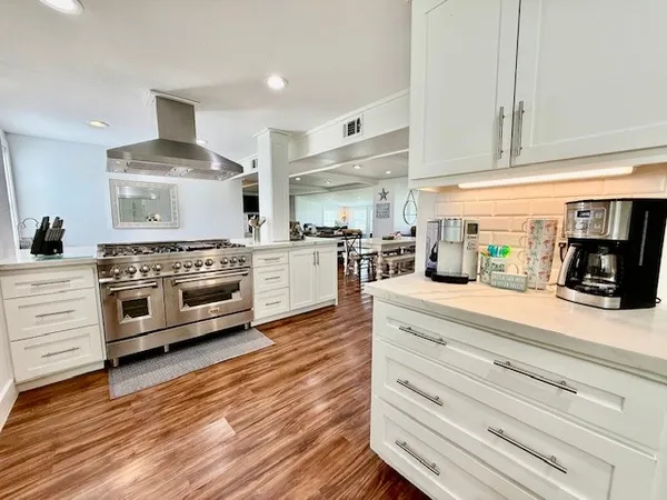a large kitchen with stainless steel appliances a dining table chairs and a wooden floor
