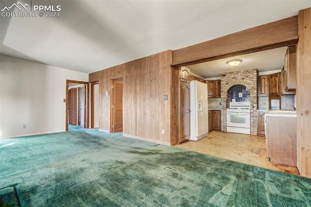 23555 Murphy Road Calhan, CO 80808 - Photo 25 of 49 Kitchen with white appliances, wood walls, and light colored carpet