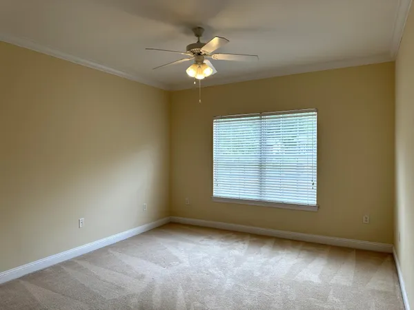 an empty room with a chandelier fan and windows