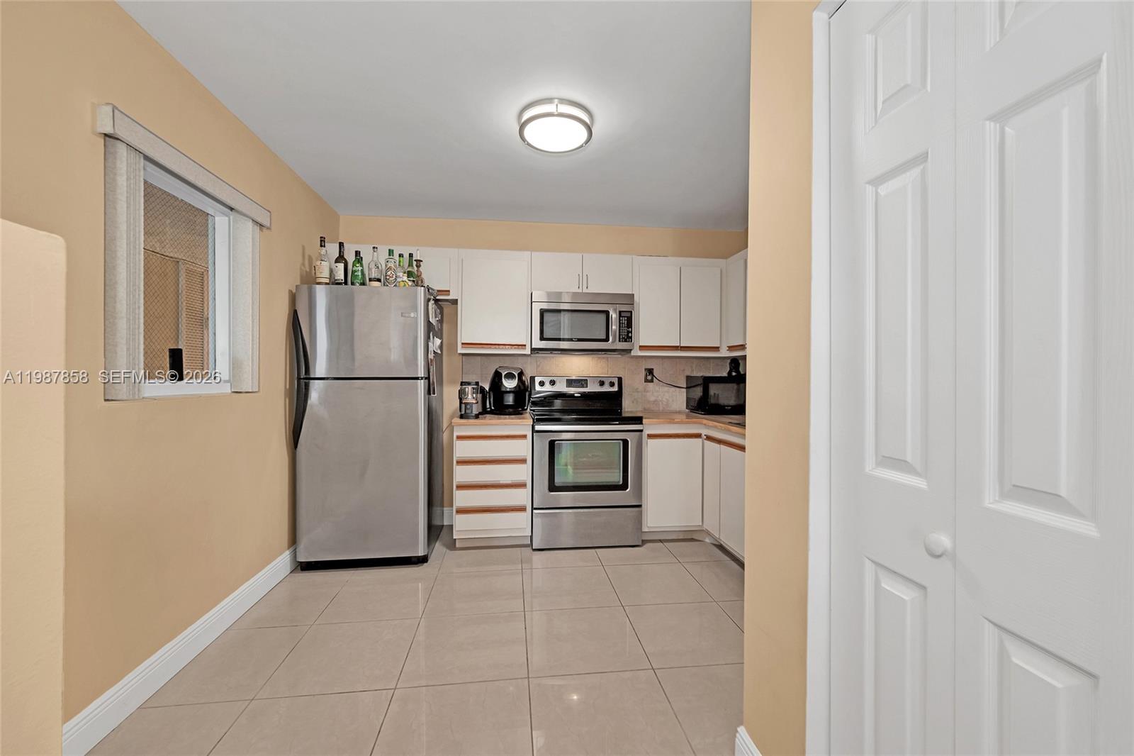 10441 Mahogany Key Circle, Unit 101 Miami, FL 33196 - Photo 12 of 26 a kitchen with white cabinets and stainless steel appliances