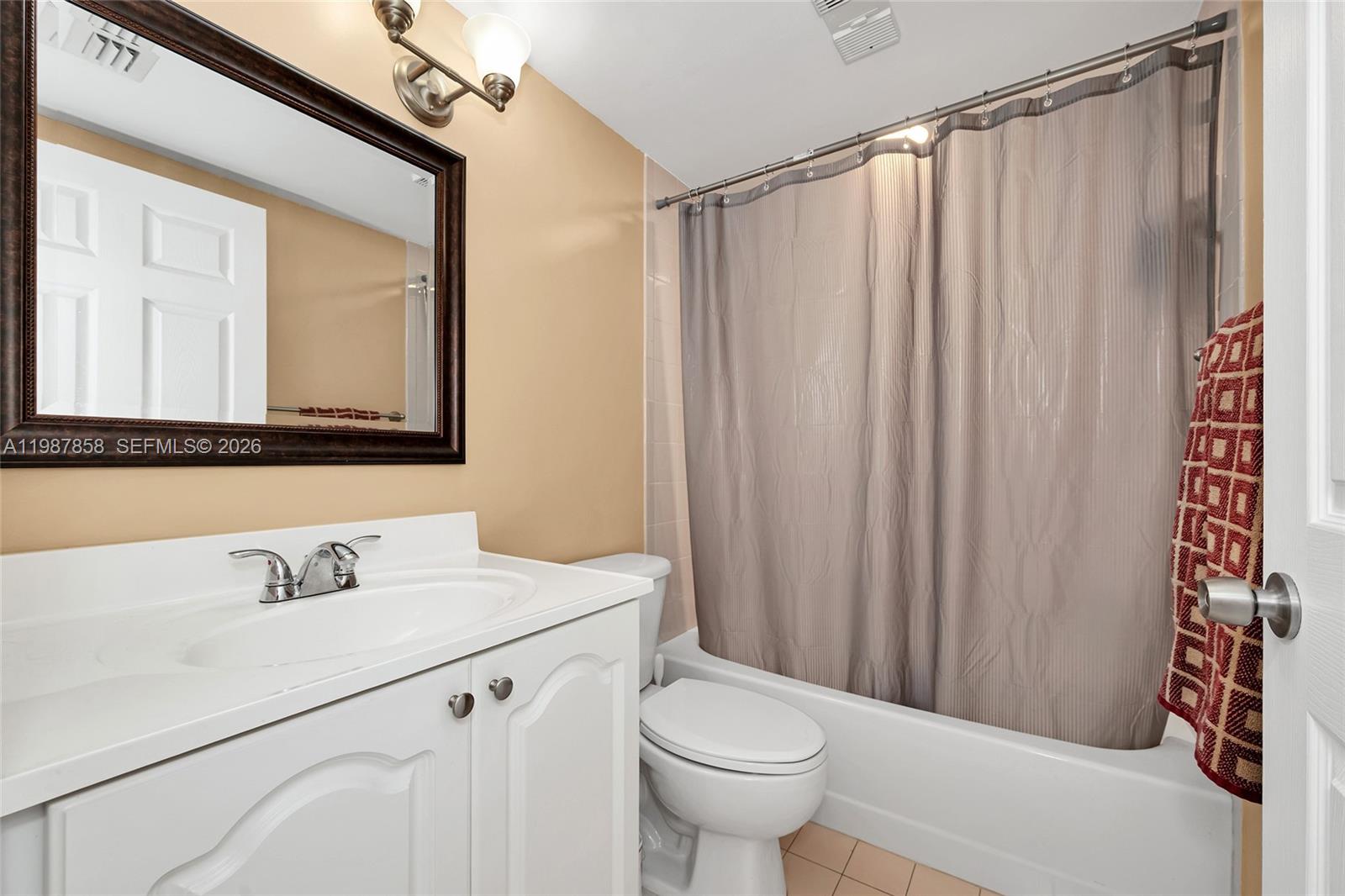 10441 Mahogany Key Circle, Unit 101 Miami, FL 33196 - Photo 19 of 26 a bathroom with a sink a toilet a mirror and shower curtain