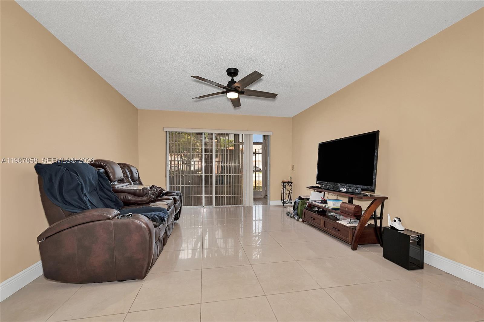 10441 Mahogany Key Circle, Unit 101 Miami, FL 33196 - Photo 8 of 26 a living room with furniture a ceiling fan a flat screen tv and a large window