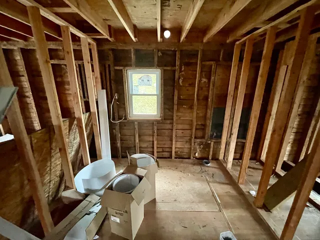 a view of an empty room with wooden floor and furniture
