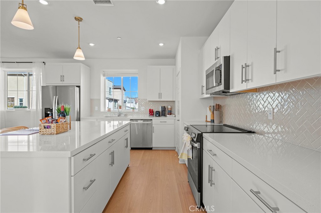 131 Ruby Road Rancho Mission Viejo, CA 92694 - Photo 20 of 65 a kitchen with a sink dishwasher and white cabinets with wooden floor