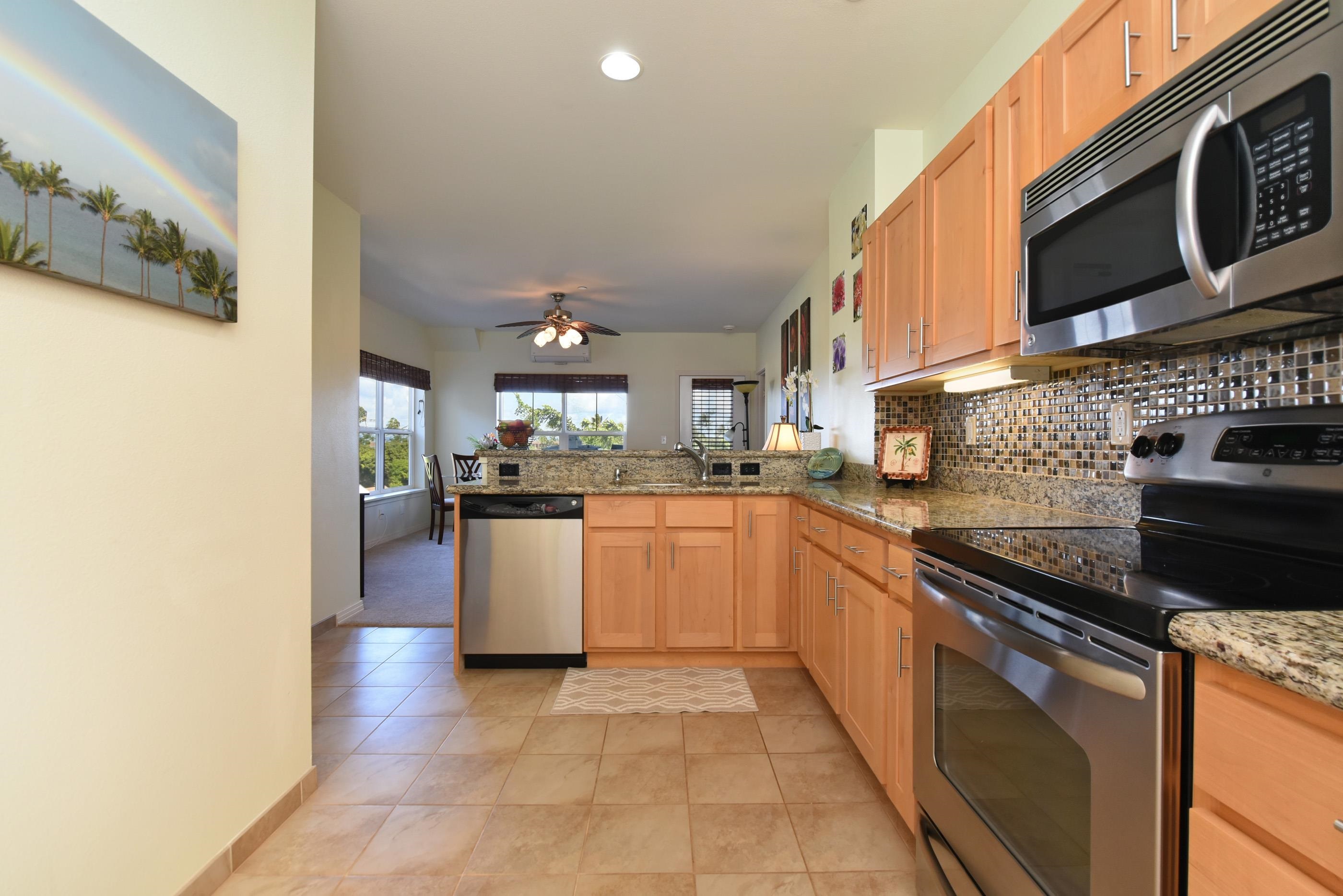 3708 Lower Honoapiilani Road, Unit E30 Lahaina, HI 96761 - Photo 3 of 30 a kitchen with stainless steel appliances granite countertop a stove a sink and a microwave