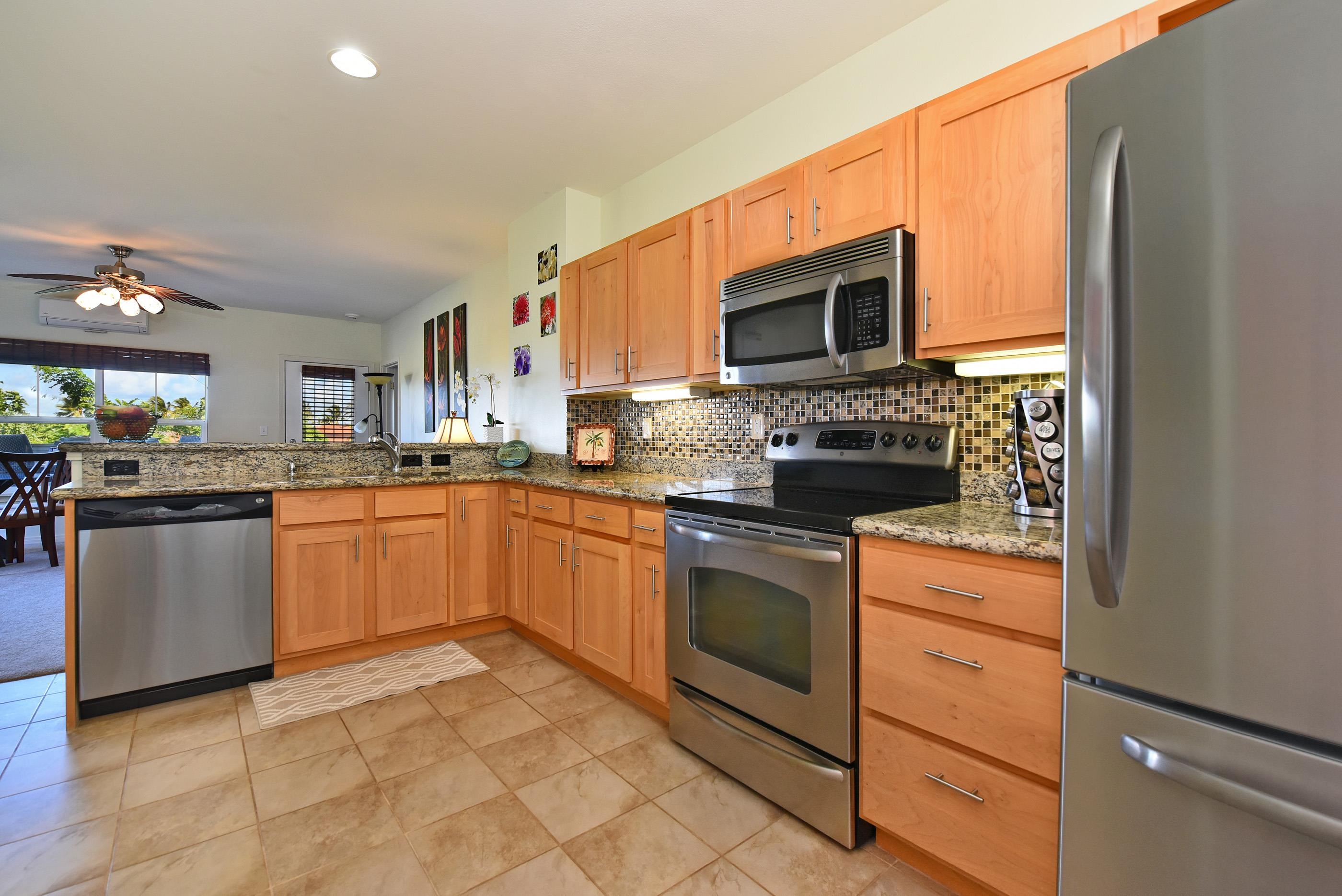 3708 Lower Honoapiilani Road, Unit E30 Lahaina, HI 96761 - Photo 4 of 30 a kitchen with stainless steel appliances granite countertop a stove top oven a sink dishwasher and a microwave oven with white cabinets