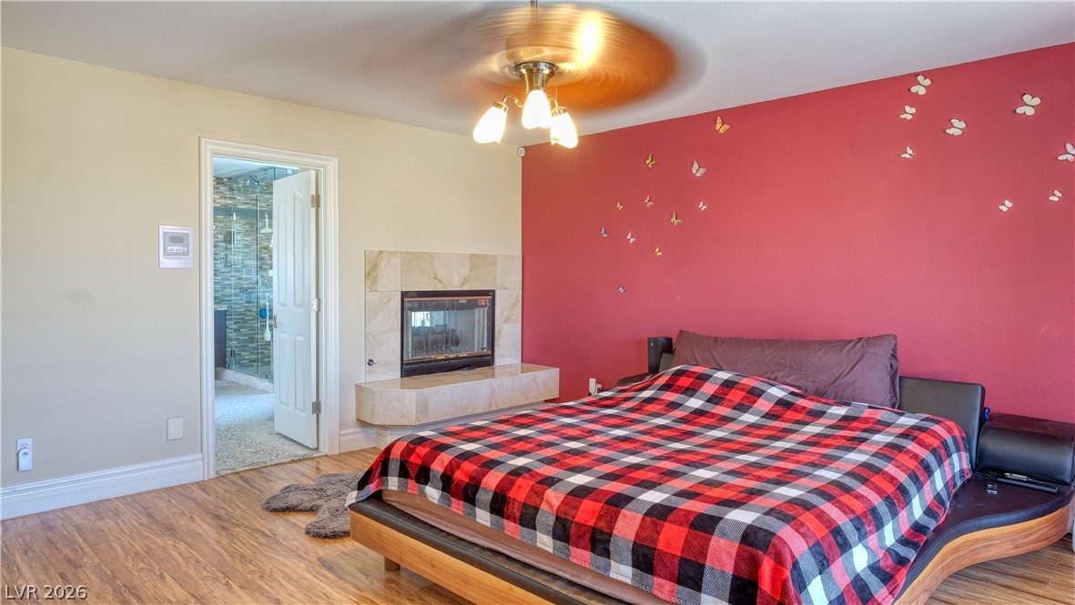 3704 North Campbell Road Las Vegas, NV 89129 - Photo 29 of 38 A well-appointed primary bedroom with a cozy fireplace and rich hardwood flooring.