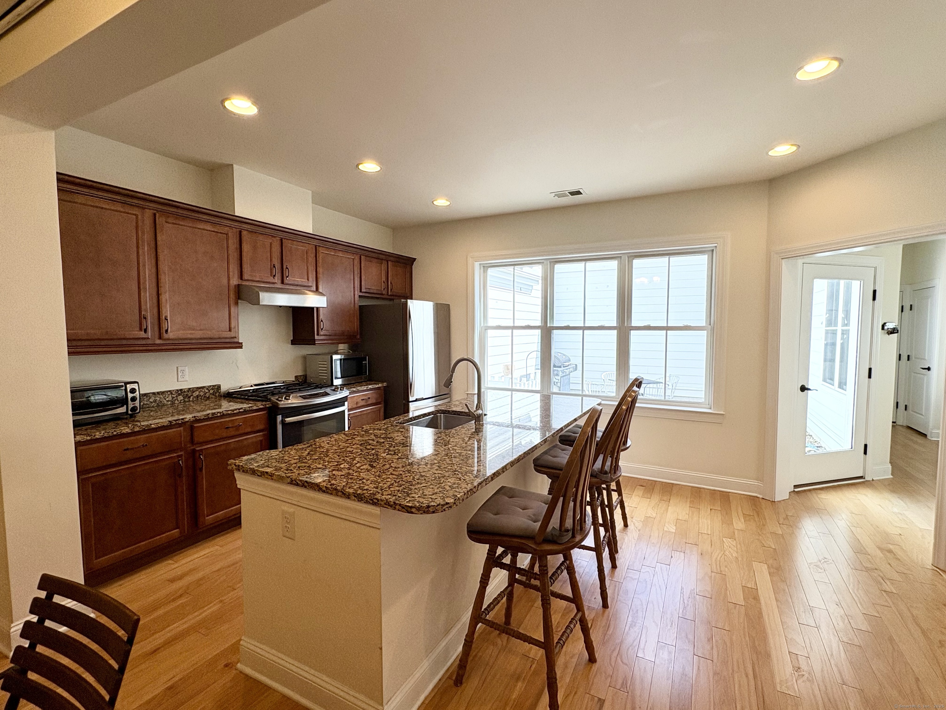 47 Sherwood Street, Unit 47 Mansfield, CT 06268 - Photo 4 of 21 a kitchen with stainless steel appliances granite countertop a stove a refrigerator a sink a microwave and white cabinets with wooden floor
