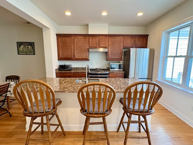 a kitchen with stainless steel appliances granite countertop a dining table chairs and a refrigerator