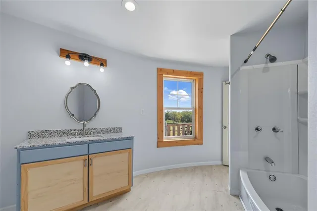 a bathroom with a granite countertop sink a mirror and a bathtub