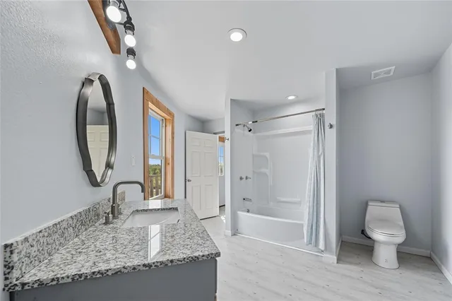 a bathroom with a granite countertop sink toilet and shower