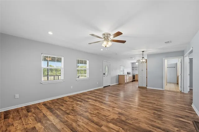 a view of empty room with wooden floor and fan