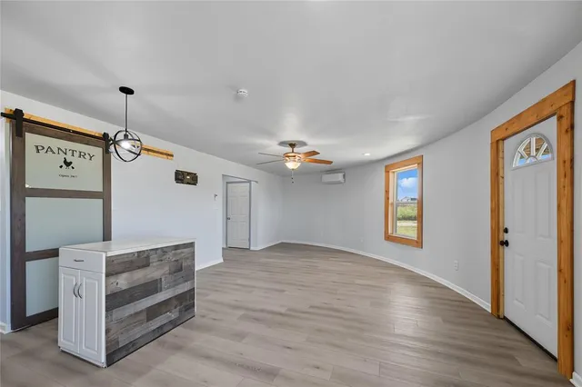 a view of an empty room with a window and wooden floor