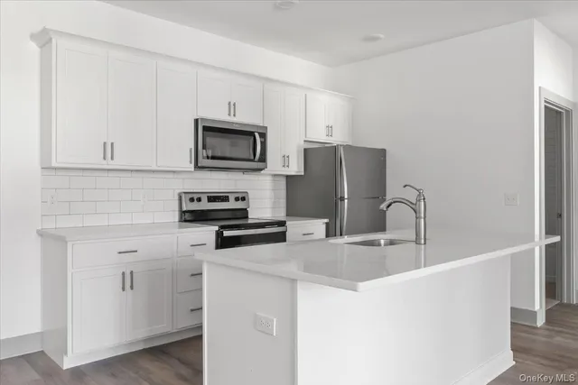 a kitchen with stainless steel appliances granite countertop a refrigerator a stove a sink and white cabinets