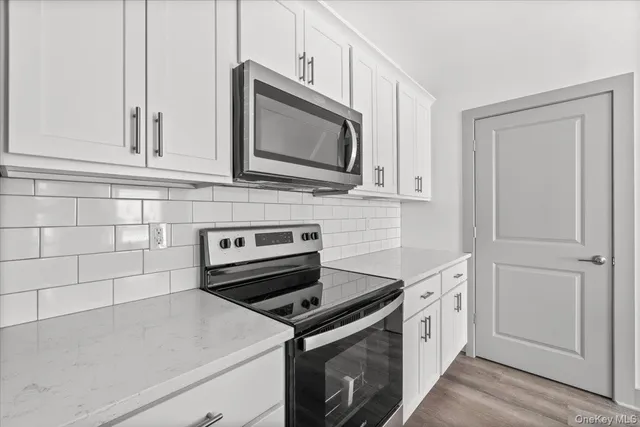 a kitchen with granite countertop white cabinets stainless steel appliances and wooden floor