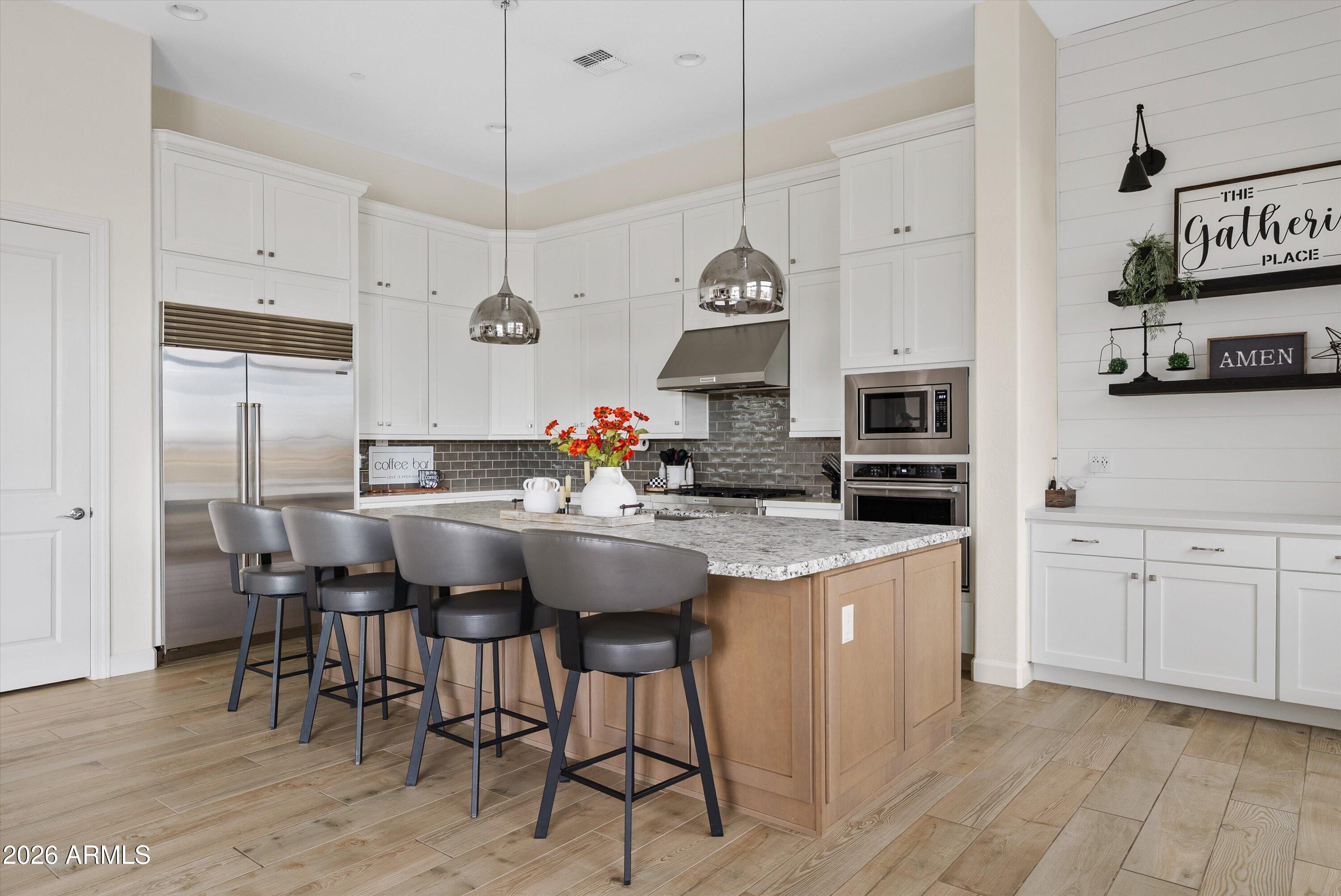 7002 South Portland Avenue Gilbert, AZ 85298 - Photo 17 of 40 a kitchen with stainless steel appliances kitchen island granite countertop a table chairs sink and white cabinets