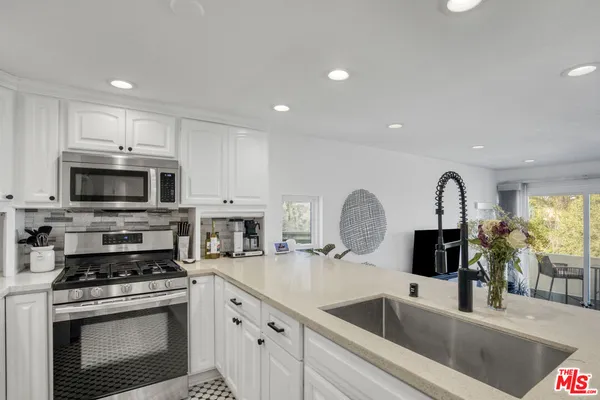 a kitchen with stainless steel appliances granite countertop a sink a stove and a microwave
