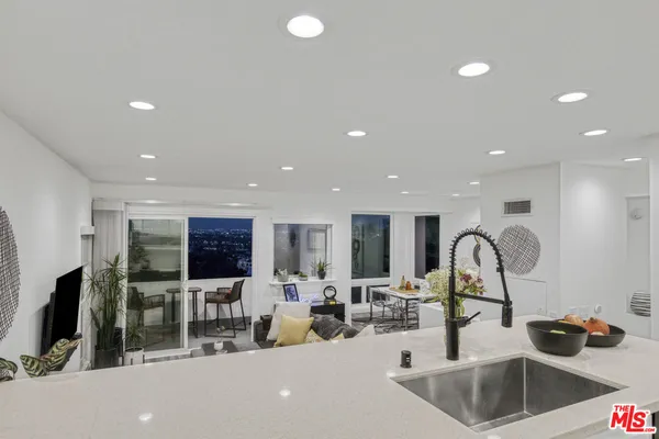 a kitchen with counter top a sink and a refrigerator a table