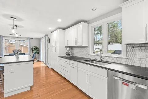 a large kitchen with stainless steel appliances granite countertop a sink and wooden cabinets
