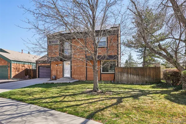 a view of a brick house next to a yard with large trees