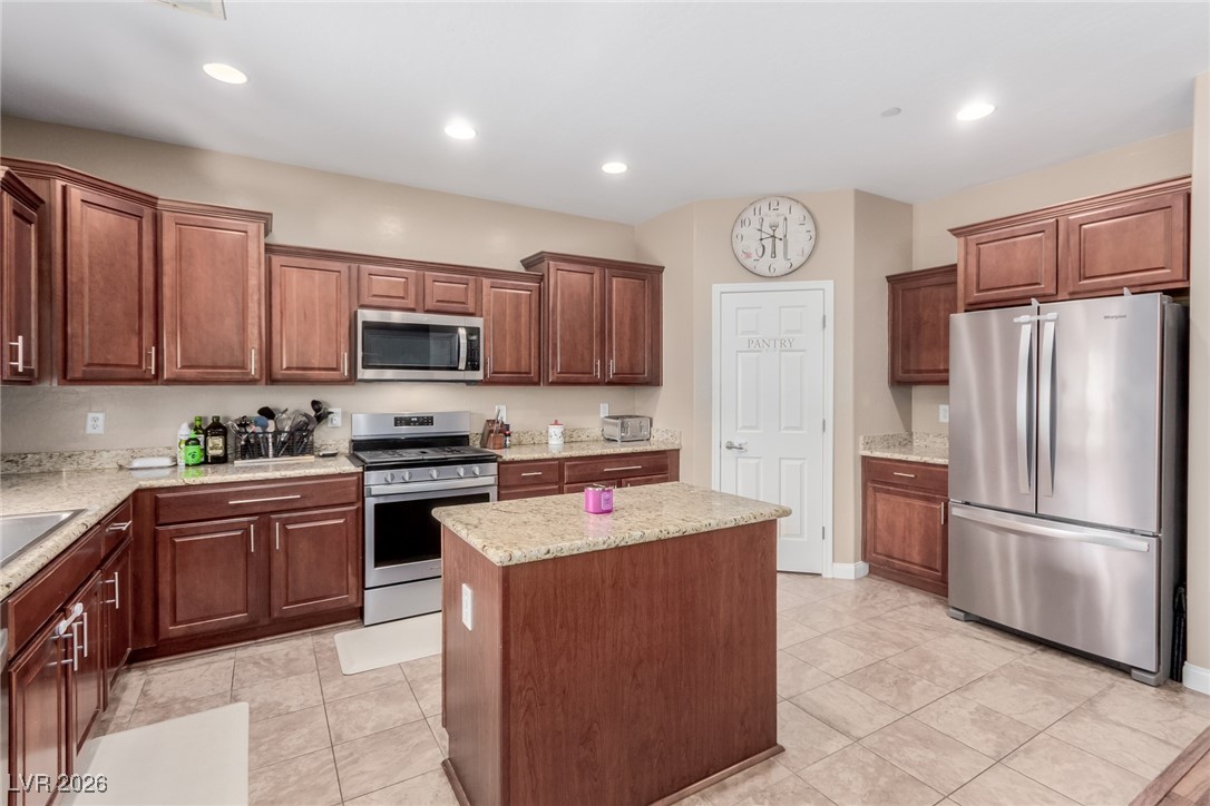 113 Lovage Street Henderson, NV 89002 - Photo 12 of 27 Kitchen featuring appliances with stainless steel finishes, recessed lighting, a center island, light tile patterned floors, and light stone counters