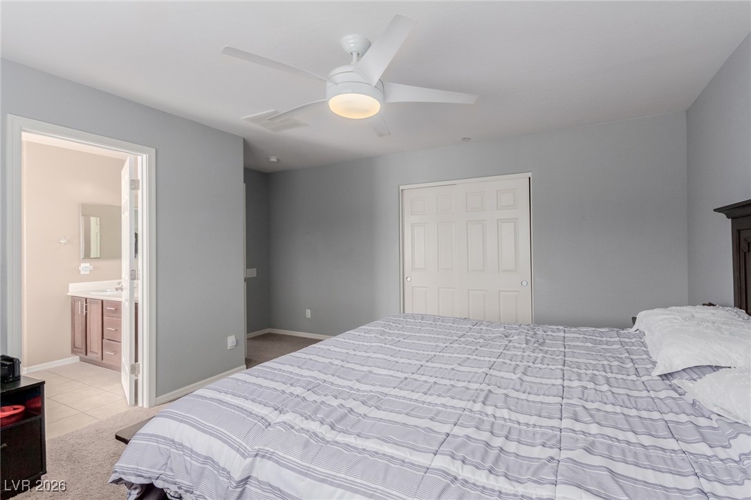 113 Lovage Street Henderson, NV 89002 - Photo 17 of 27 Bedroom featuring light carpet, ceiling fan, light tile patterned floors, and ensuite bathroom