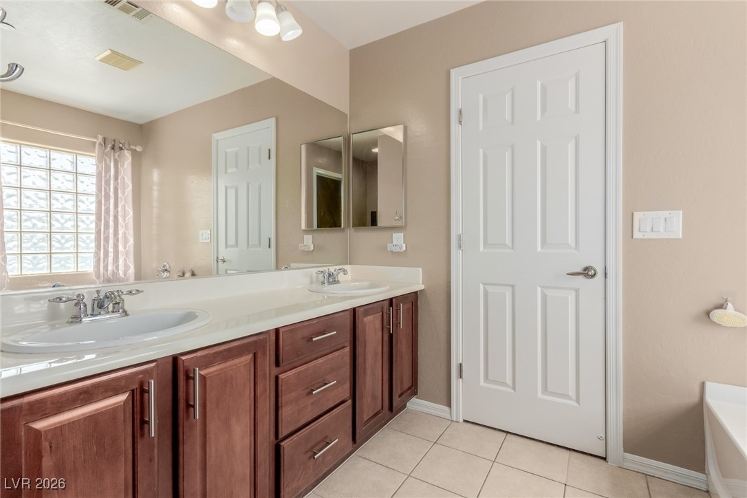 113 Lovage Street Henderson, NV 89002 - Photo 18 of 27 Bathroom with light tile patterned flooring, double vanity, and a garden tub