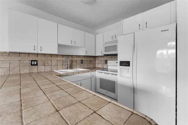 a kitchen with granite countertop a stove a sink and a refrigerator