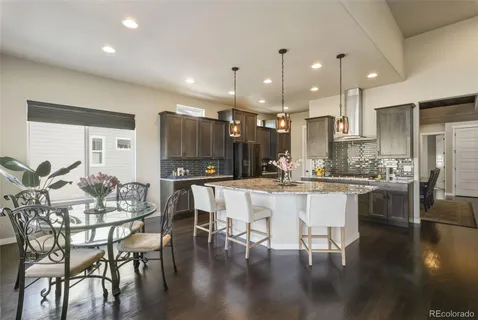 a kitchen with stainless steel appliances kitchen island granite countertop a dining table chairs and white cabinets