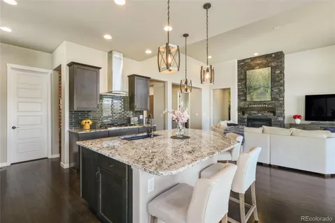 a kitchen with kitchen island granite countertop wooden floor and refrigerator
