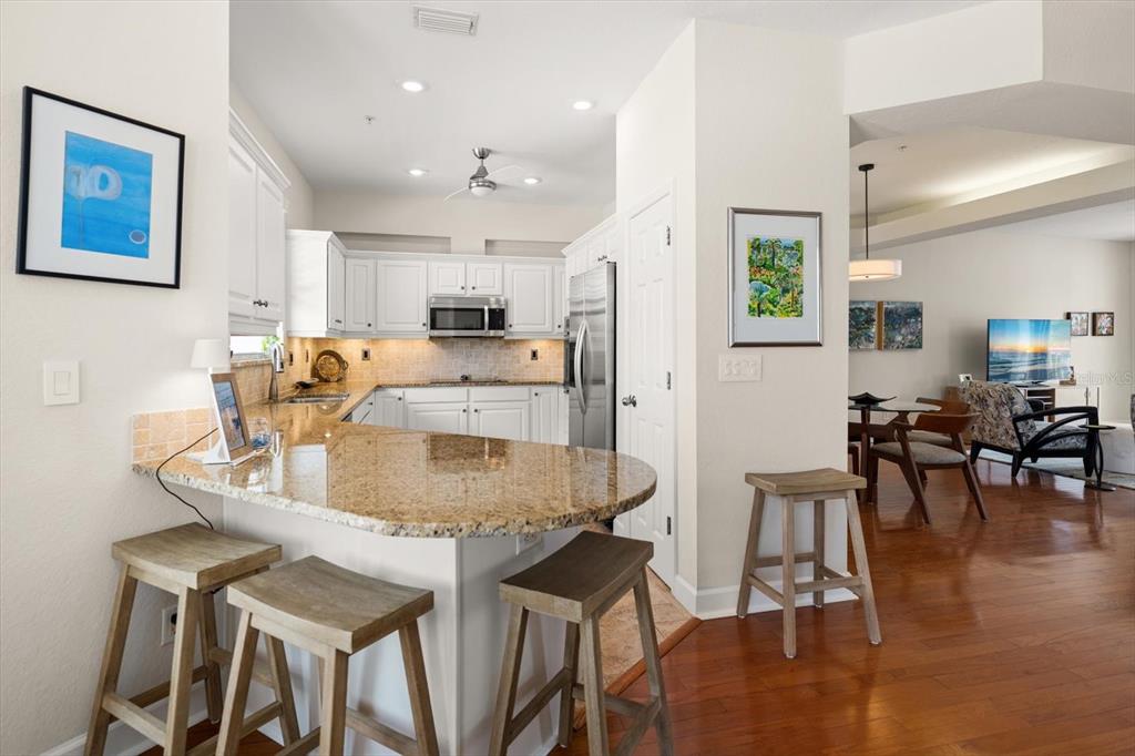 103 Shoals Circle North Redington Beach, FL 33708 - Photo 19 of 69 a kitchen with stainless steel appliances granite countertop a stove a refrigerator a kitchen island a dining table and chairs with wooden floor
