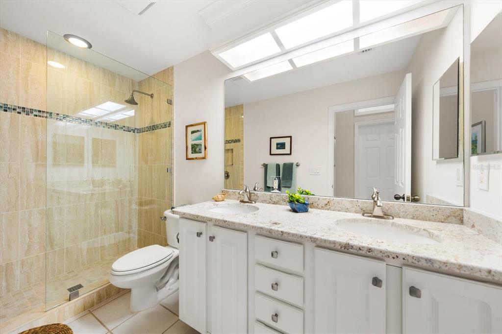 103 Shoals Circle North Redington Beach, FL 33708 - Photo 42 of 69 a bathroom with a granite countertop sink toilet a large mirror a shower and vanity