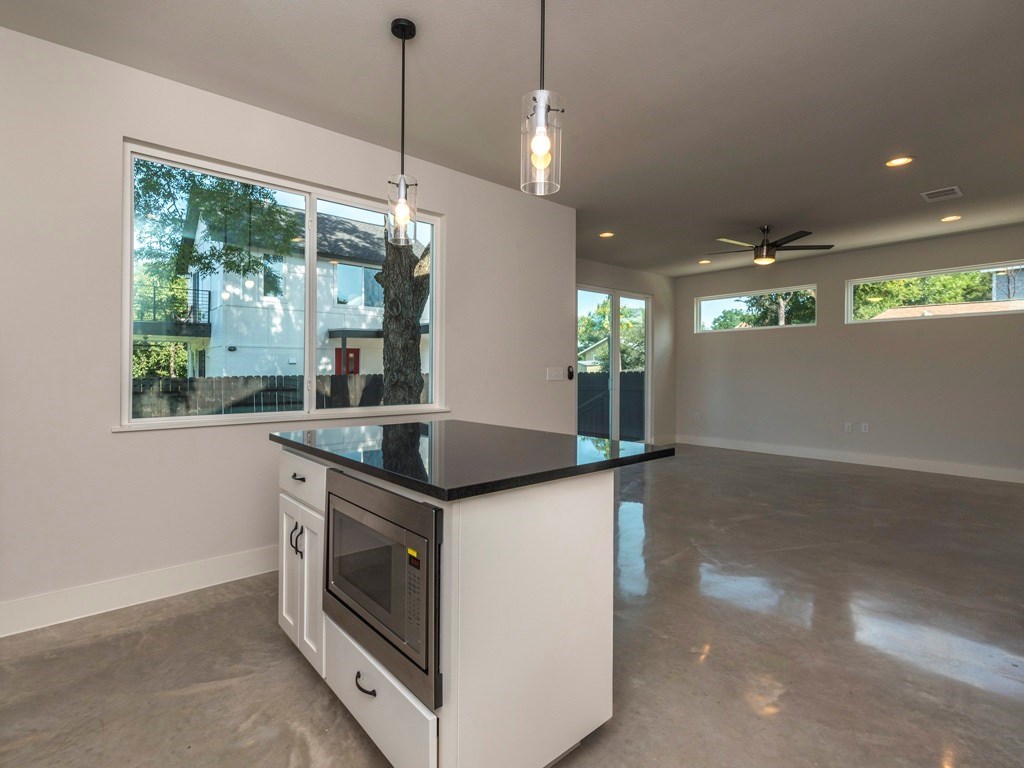 1182 Ridgeway Drive, Unit A Austin, TX 78702 - Photo 11 of 27 Kitchen featuring concrete flooring, stainless steel microwave, a kitchen island, a ceiling fan, and white cabinets