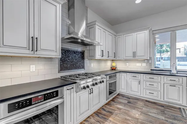 a kitchen with stainless steel appliances granite countertop a stove and a white cabinets