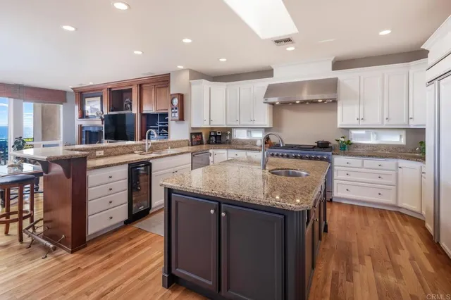 a kitchen with a sink a center island stainless steel appliances and cabinets