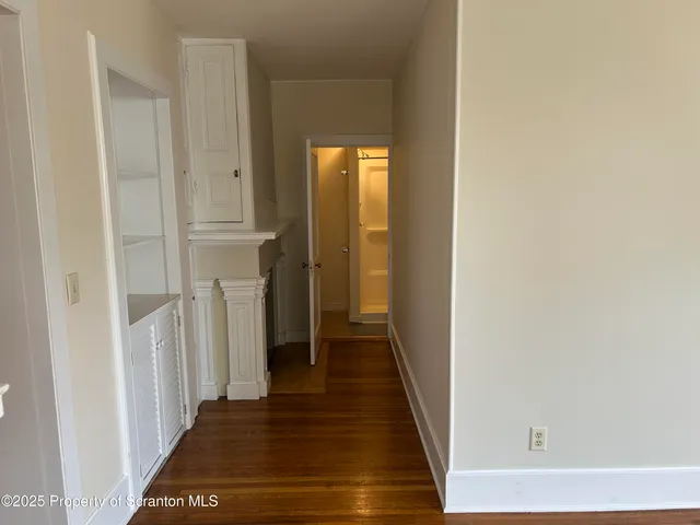 a view of a hallway with wooden floor and closet