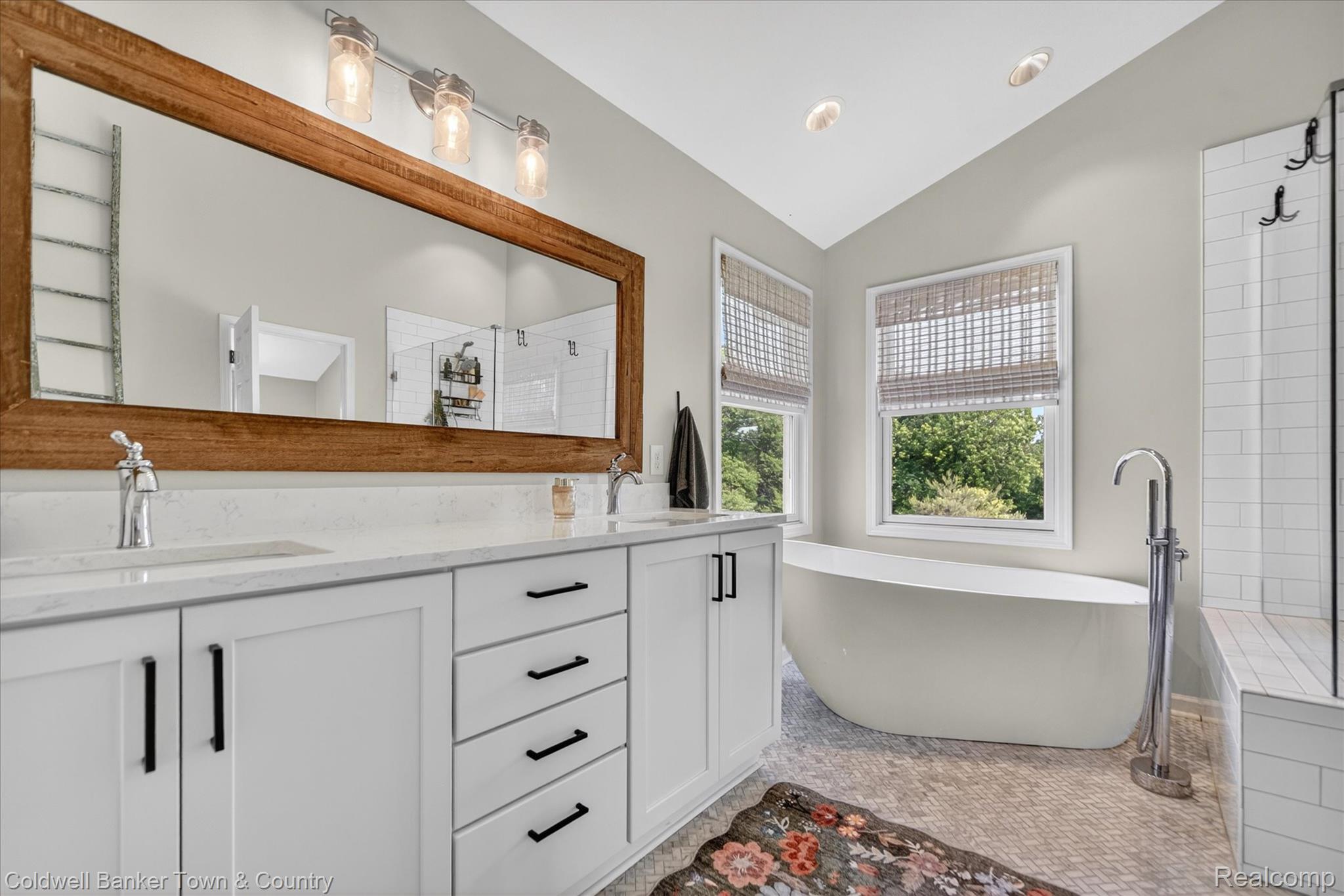 918 Gray Fox Court Howell, MI 48843 - Photo 33 of 84 Double vanity with white cabinetry and quartz countertops, featuring a large wood-framed mirror