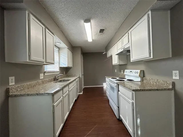 a kitchen with granite countertop kitchen island stainless steel appliances a sink stove top oven and cabinets