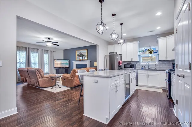 a kitchen with stainless steel appliances granite countertop a refrigerator a sink dishwasher a dining table and chairs with wooden floor