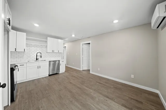 a large white kitchen with a sink and dishwasher a stove with wooden floor