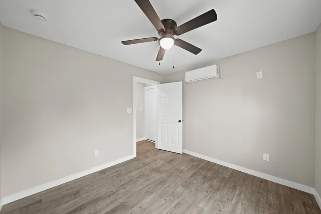 an empty room with wooden floor and ceiling fan