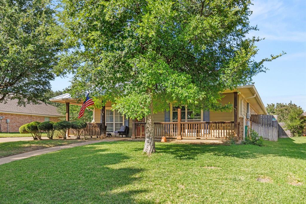 10609 Aquilla Trail Waco, TX 76708 - Photo 2 of 30 Front exterior featuring a covered porch with wood railing, mature trees, and a manicured lawn