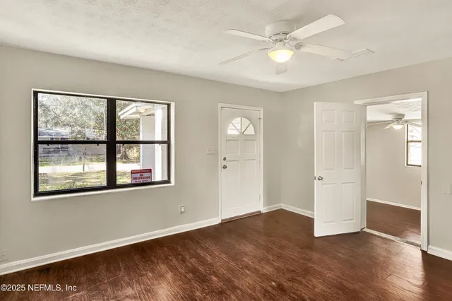 an empty room with wooden floor and windows